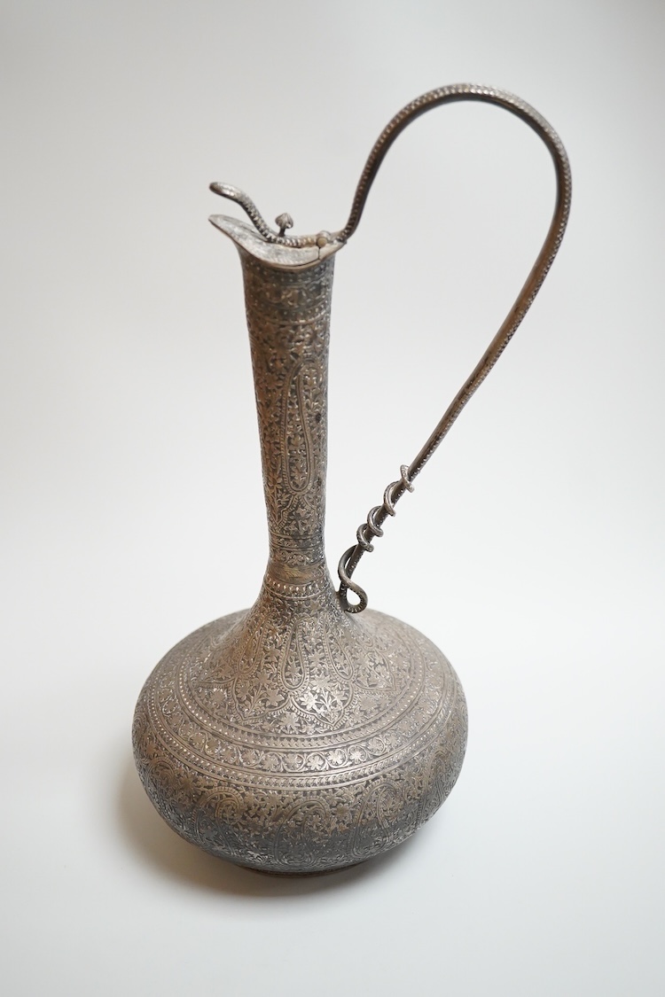 A late 19th century Indian white metal ewer, with extensive foliate decoration and cobra handle, height 30.3cm.